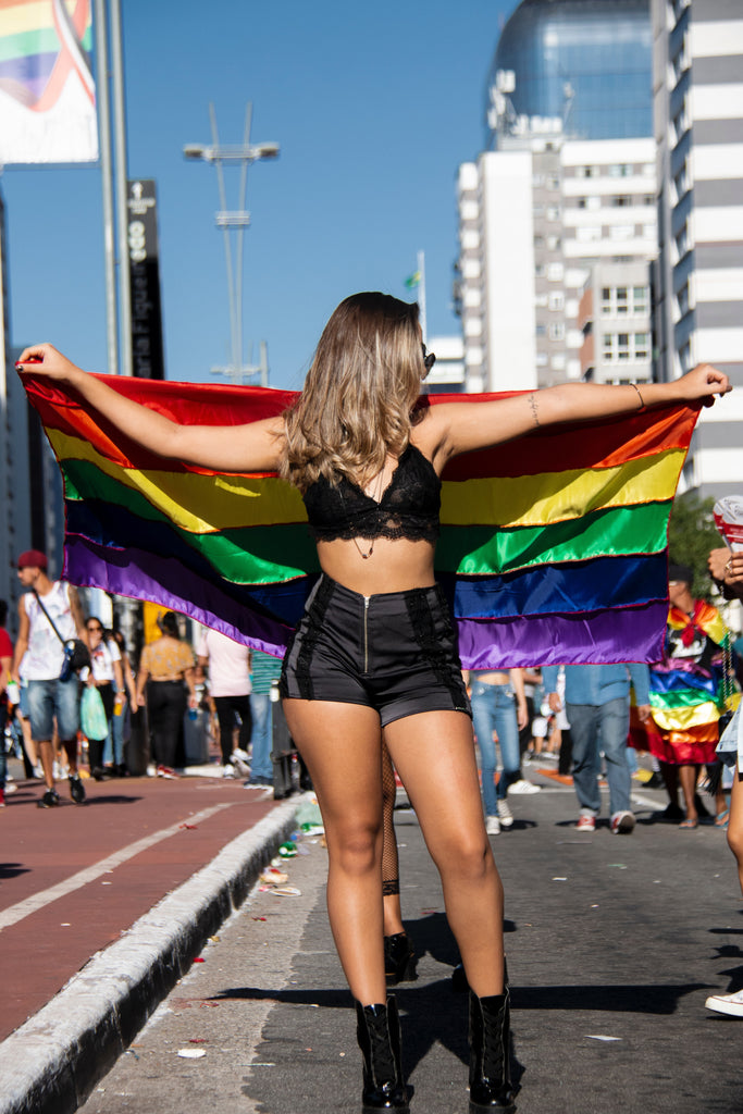 sexy girl holding rainbow pride flag behind her back and arms stretched out