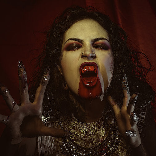 Woman dressed as Vampiress with long metallic nails and fangs dripping in our edible non-toxic fake blood.